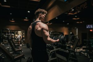 Sportif réalisant un curl avec haltère dans une salle de musculation, coude en flexion
