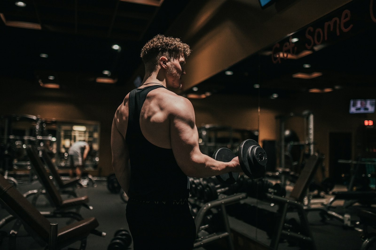 Sportif réalisant un curl avec haltère dans une salle de musculation, coude en flexion
