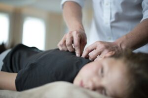 Praticien réalisant un traitement manuel des cervicales sur un patient allongé